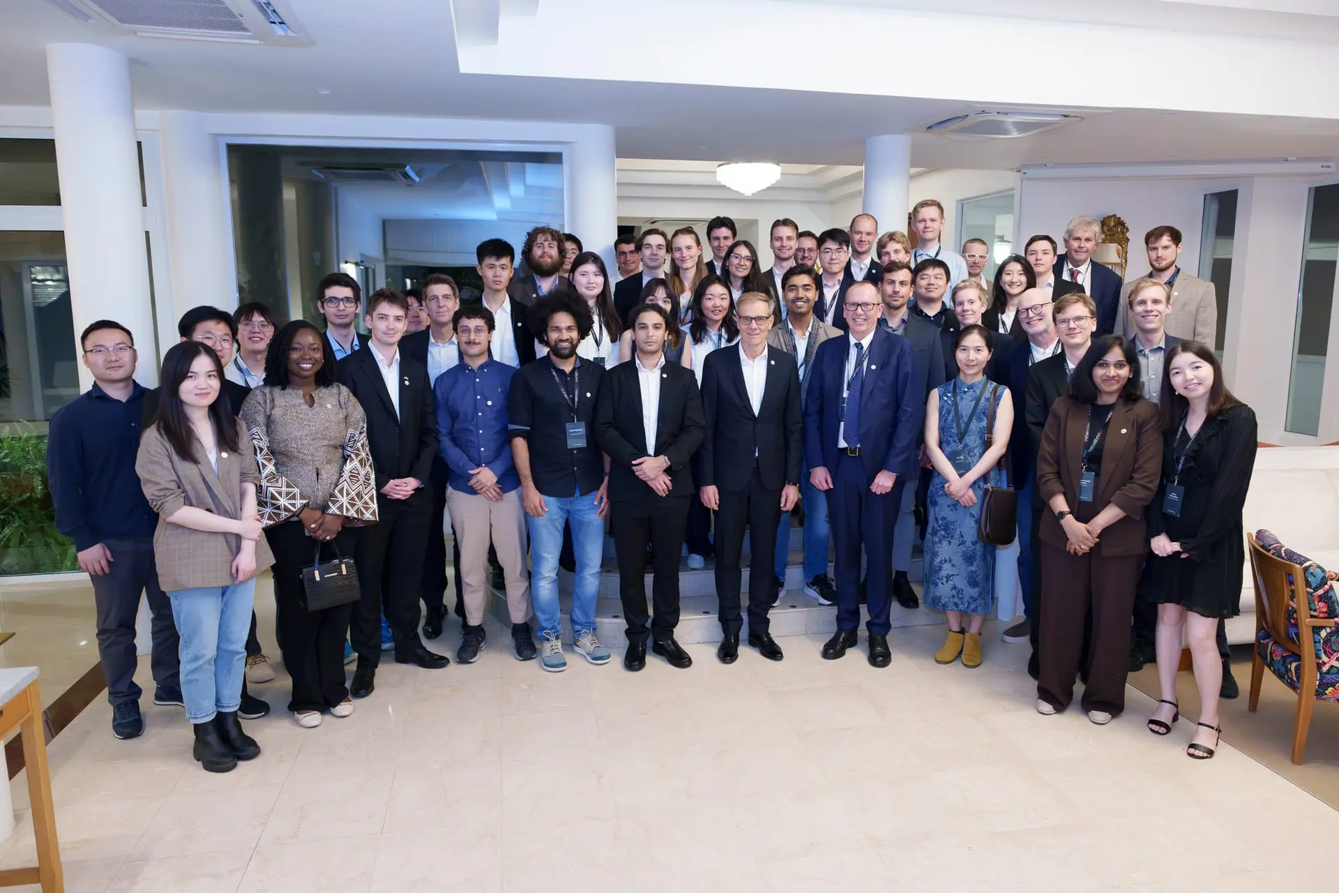 A large group photo of WASP PhD students and hosts in a bright reception room