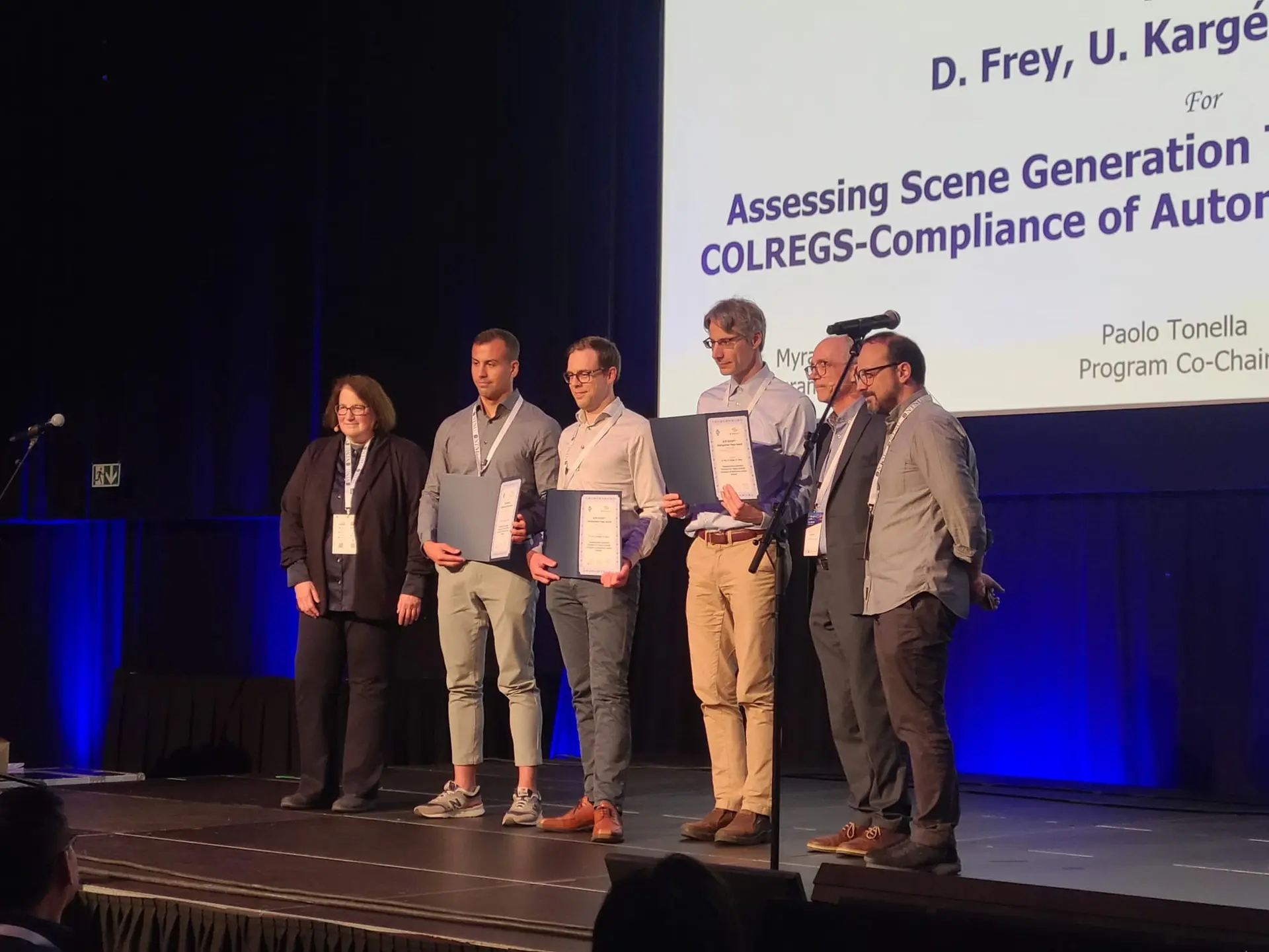 The three authors holding their award certificates on stage at ISSTA 2025