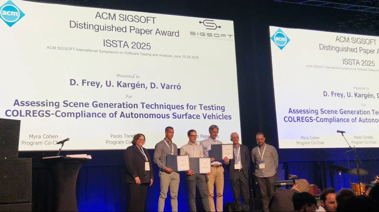 The award ceremony on stage at ISSTA 2025, with the slide naming D. Frey, U. Kargén and D. Varró for the ACM SIGSOFT Distinguished Paper Award