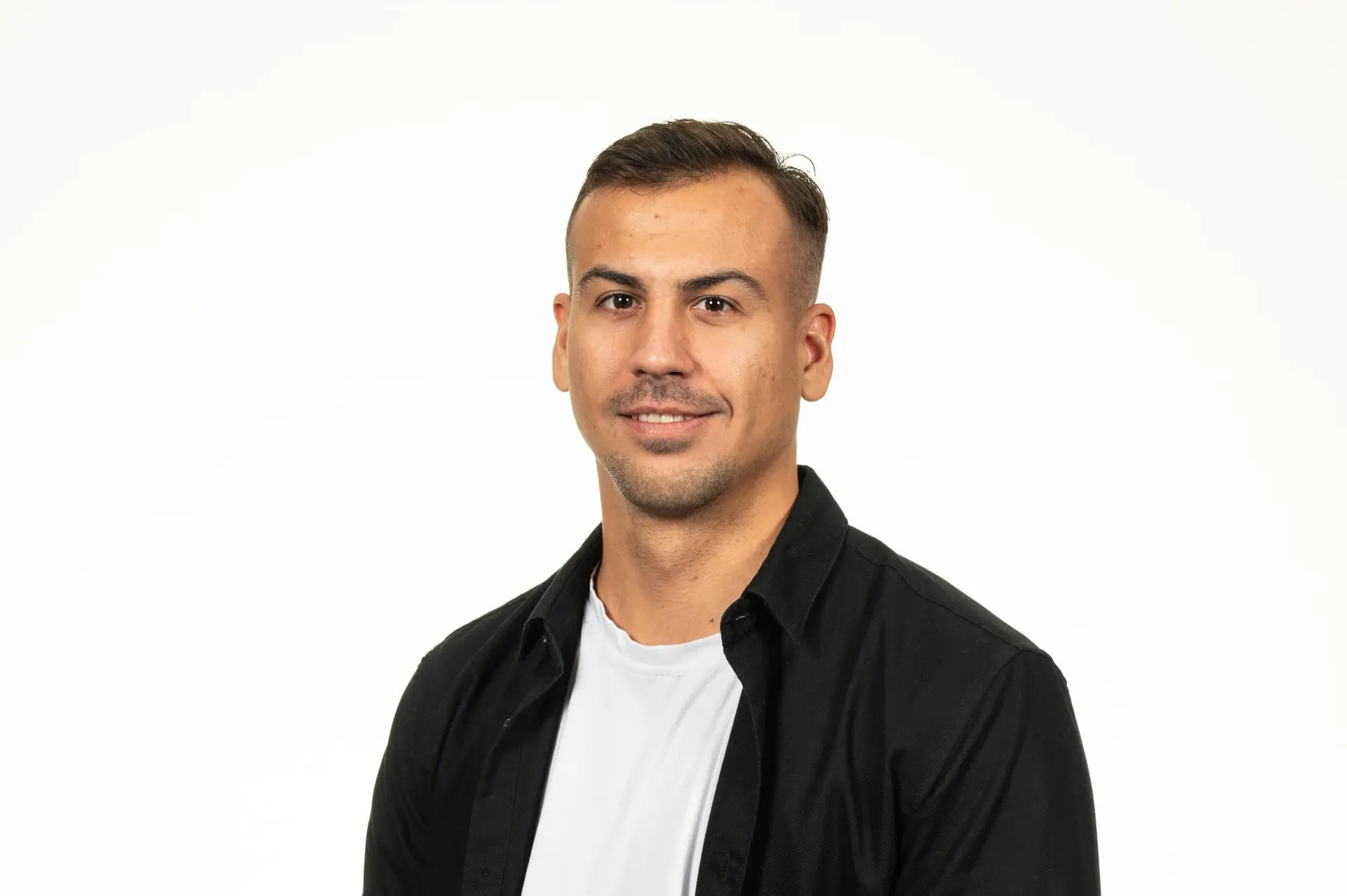 Studio portrait of Dominik Frey in a dark shirt against a white background
